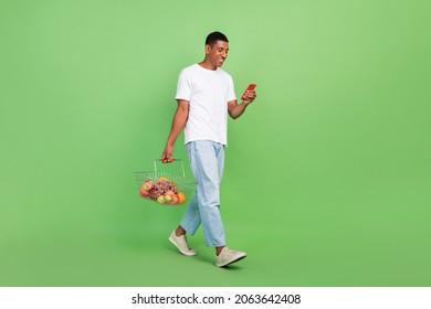 Full size profile side photo of young afro guy type browse cellphone shopping mall isolated over green color background - Powered by Shutterstock