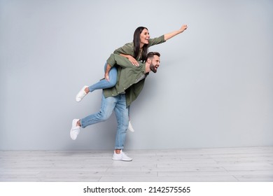 Full size profile side photo of young cheerful couple have fun walk strong look empty space isolated over grey color background