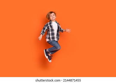 Full size profile side photo of young cheerful boy have fun jump up isolated over orange color background - Shutterstock ID 2144871455