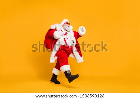Full size profile side photo of funky fat santa claus with huge abdomen hold gift wish bag go walk travel around world on christmas night eve wear x-mas hat suspenders isolated bright color background