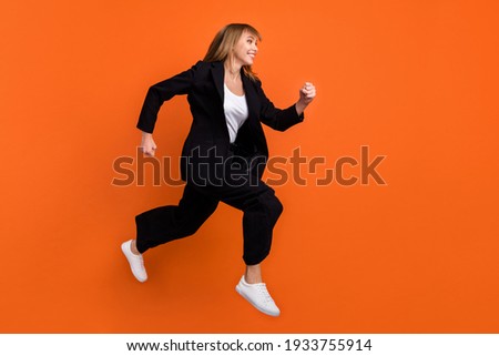 Full size profile side photo of young beautiful charming girl look copyspace running fast in air isolated on orange color background