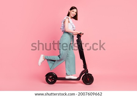 Full size profile side photo of young girl happy positive smile driver trip weekend scooter isolated over pink color background