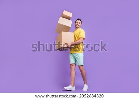 Full size profile side photo of young guy happy positive smile hold cardboard delivery isolated over purple color background