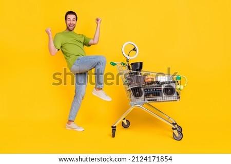 Full size profile side photo of young man celebrate victory lottery swap unused stuff isolated over yellow color background