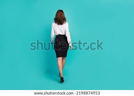 Full size rear behind photo of successful girl walking isolated on aquamarine color background