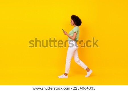 Full size side profile photo of young pretty attractive womna wear casual outfit hold phone read message dont look road isolated on yellow color background