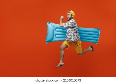 Full size side view young happy tourist man wear beach shirt hat hold inflatable mattress jump high run isolated on plain orange background studio portrait. Summer vacation sea rest sun tan concept