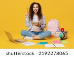 Full size smart fun young black teen girl student wear casual clothes backpack bag sit read book pont index finger up isolated on plain yellow color background. High school university college concept