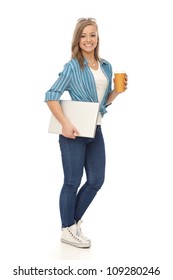 Full size young blonde woman walking with laptop and coffee, smiling.