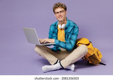 Full Size Young Boy Teen Student In Casual Clothes Backpack Headphones Glasses Sit Hold Work On Laptop Computer Isolated On Violet Background Studio Education In High School University College Concept