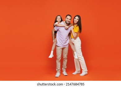 Full size young fun happy parents mom dad with child kid daughter teen girl in basic t-shirts giving piggyback to daughter isolated on yellow background studio Family day parenthood childhood concept. - Shutterstock ID 2147684785