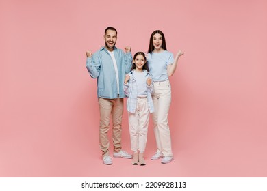 Full Size Young Parents Mom Dad With Child Kid Daughter Teen Girl In Blue Clothes Do Winner Gesture Celebrate Clenching Fists Say Yes Isolated On Plain Pastel Light Pink Background. Family Day Concept