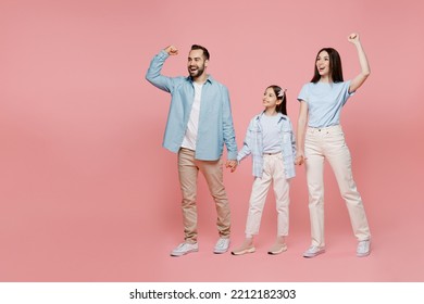 Full Size Young Parents Mom Dad With Child Kid Daughter Teen Girl In Blue Clothes Do Winner Gesture Celebrate Clenching Fists Say Yes Isolated On Plain Pastel Light Pink Background. Family Day Concept