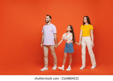 Full Size Young Smiling Fun Happy Parents Mom Dad With Child Kid Daughter Teen Girl Wear Basic T-shirts Walking Go Hold Hands Isolated On Yellow Background. Family Day Parenthood Childhood Concept.