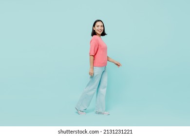 Full size young smiling happy woman of Asian ethnicity 20s wearing pink sweater walk going look camera isolated on pastel plain light blue color background studio portrait. People lifestyle concept - Powered by Shutterstock