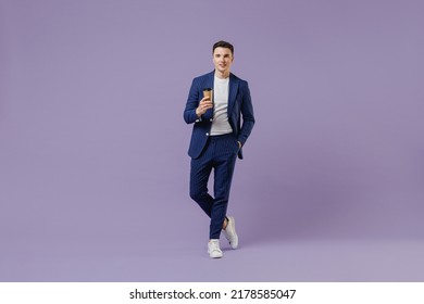 Full size young successful employee business man lawyer 20s wear formal blue suit white t-shirt hold takeaway delivery craft paper brown cup coffee isolated on pastel purple background studio portrait - Powered by Shutterstock