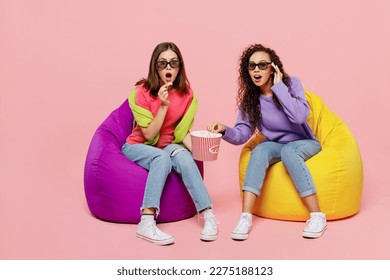 Full size young two friends shocked surprised amazed astonished women in 3d glasses watching movie film in cinema sit in bag chair isolated on pastel plain light pink color background studio portrait - Powered by Shutterstock