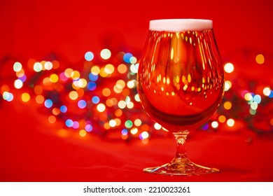 Full Snifter Glass Of Lager Beer With Blurred Christmas Lights On Red Background