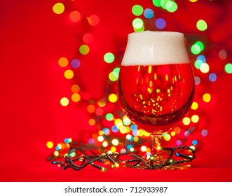 Full Snifter Glass Of Lager Of Pilsner Beer With Christmas Lights On Red Background