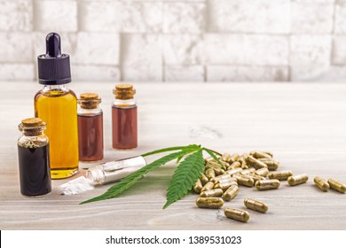 Full Spectrum Cannabidiol CBD Oils, Capsules And Crystals Isolate On Wooden Backdrop With Hemp Leaf