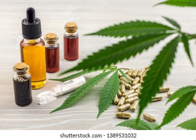 Full spectrum Cannabidiol CBD oils, capsules and crystals isolate on wooden backdrop with hemp leaf