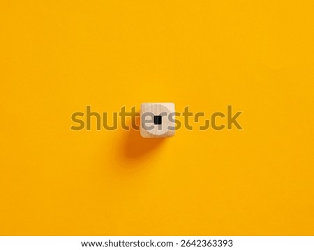 Full stop or dot punctuation mark on a wooden cube on vibrant yellow background. To put an end or to stop concepts.