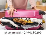 Full suitcase concept, hand of asian young woman, girl packing, preparing luggage case, luggage of clothes, female unable to close bag while sitting on sofa at home, travel trip or journey voyage.