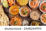 Full table of Indian food captured from above: A visually stunning image showcasing a wide array of colorful and aromatic Indian dishes, offering a feast for the eyes and the palate.