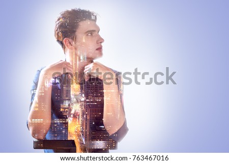 Full of thoughts. Handsome pleasant nice man leaning on the chair and looking aside while being full of thoughts