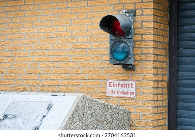 A full traffic light is fixed to the outside wall of a building instead of a pole, the bright lenses face the street like a watchful eye and turn the corner into an intersection.