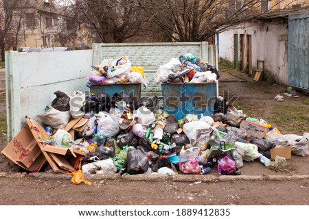Full trash can. Trash can filled with trash. Trash can packed to overflowing with rubbish. The bin is filled with rubbish.