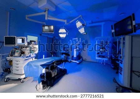 Full view of advanced robotic operating room suite. Wide shot of a modern hospital operating theater with all surgical equipment and blue light.