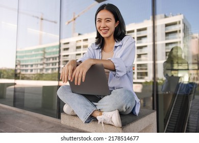 Full View Of Attractive Student Woman Look With Smile At Camera . Dark-haired Asian Lady Sitting With Laptop On The Street. Technology, Working Mood 