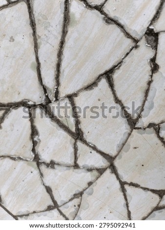 A full view of cracked and broken ceramic tiles with dark cement lines, creating an irregular abstract mosaic textured background.