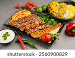 Full view of Persian Mix Kebab of minced meat and chicken With Rice and french fries and vegetables in a large traditional tray