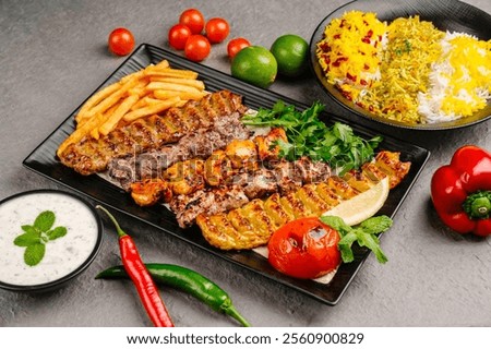 Full view of Persian Mix Kebab of minced meat and chicken With Rice and french fries and vegetables in a large traditional tray