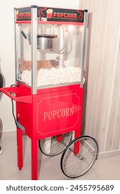 Full view of red automatic popcorn machine on its base and eye-catching text