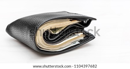 Full wallet with money on white wooden background.