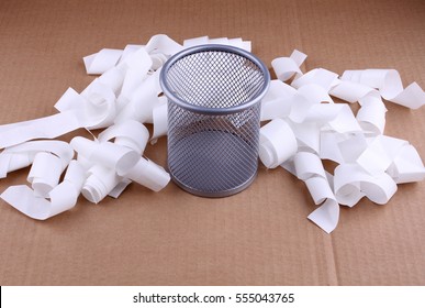 Full Wire Mesh Trash Can With Crumpled Paper Scattered Around. Isolated On Brown