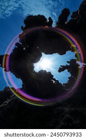 A full-circle rainbow is created in this image when the sunburst seen through an opening in the coral reef hits the dome port of the camera.
