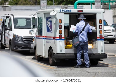 Fullerton, California / USA - August 13, 2020: A USPS (United States Parcel Service) Mail Truck And Postal Carrier Make A Delivery.