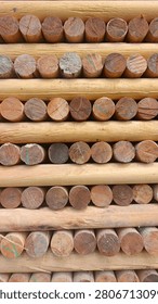 A full-frame abstract pattern of neatly stacked cylindrical wooden logs showing their cut ends