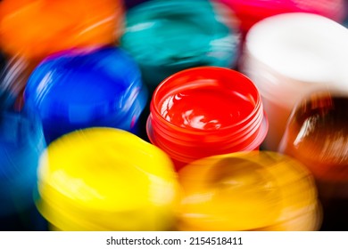 Full-frame Close-up Background Of Opened Small Gouache Paint Jars With Natural Motion Blur Around Red Jar