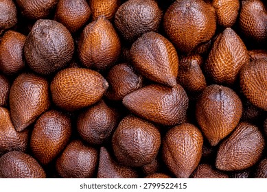 full-frame horizontal  shot featuring a large cluster of fresh salak, commonly known as snake fruit. The commercial photograph showcases the distinct scaly, reddish-brown pattern of the skin with exceptional detail and texture. The mood is earthy, rustic, and exotic, highlighting unique biodiversity and traditional tropical harvests. This professional background pattern is well-suited for botanical articles, culinary packaging, premium grocery branding, agricultural markets, and global food travel blogs.
