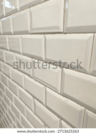 A full-frame macro view of the iconic white, beveled, rectangular (or square, depending on the actual visual) ceramic tiles found on the walls of historic Paris Metro stations.