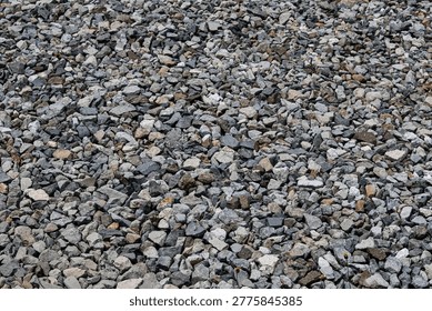A full-frame, textural close-up of a bunch of rocks. The dense arrangement of the stones in natural shades of grey.
