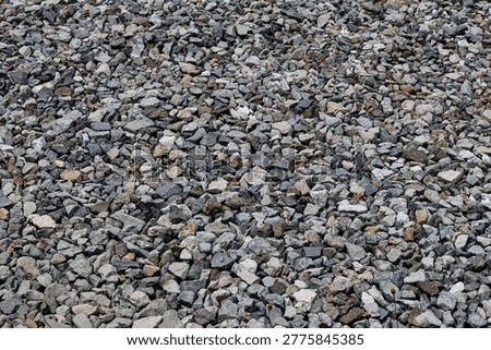A full-frame, textural close-up of a bunch of rocks. The dense arrangement of the stones in natural shades of grey.