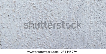 A full-frame texture of a rough, bumpy, and unevenly painted white stucco or concrete wall surface