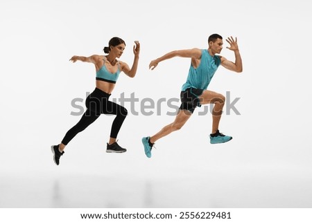 Full-length dynamic image of young athletic couple, man and woman with fit bodies in motion, running against white studio background. Concept of sport, active and healthy lifestyle, workout, fitness