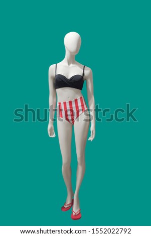 Full-length female mannequin wearing fashionable swimsuit, isolated on green background. No brand names or copyright objects.